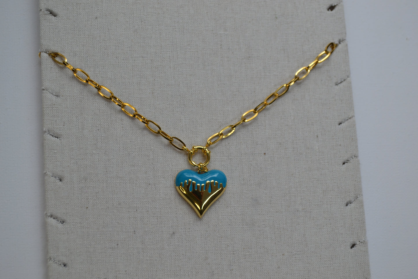 Gouden ketting met een bedel met goud en wit op een ketting stand.