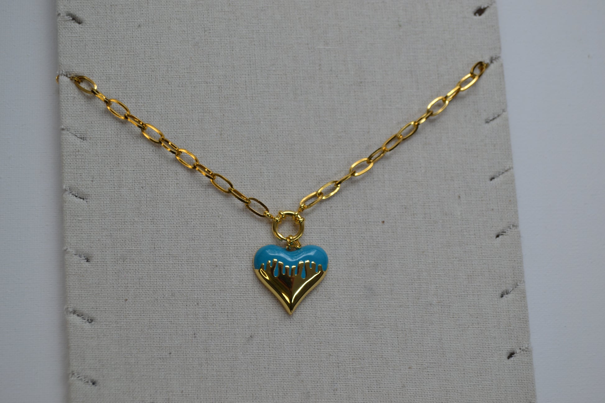 Gouden ketting met een bedel met goud en wit op een ketting stand.