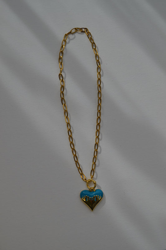 Gouden ketting met een bedel met goud en blauw op een witte achtergrond.